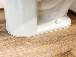 Should flooring go under or around toilet?